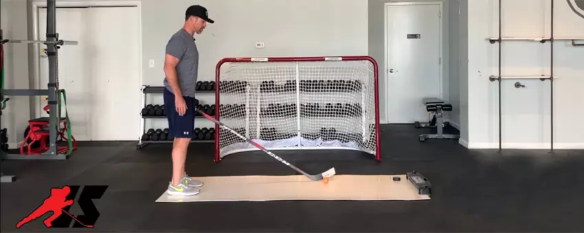 A man teaching how to shoot a hockey puck